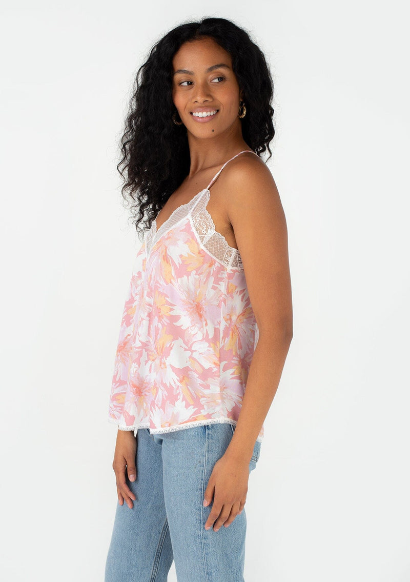[Color: Peach/Light Pink] A side facing image of a brunette model wearing a best selling lace trim camisole in a pink floral print. With adjustable spaghetti straps, a racer back, and a v neckline. 