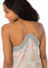 [Color: Blush/Aqua] A close up back facing image of a black model wearing a sheer pink and aqua blue paisley print chiffon camisole tank top with a lace trim v neckline, adjustable spaghetti straps, and a lace trim racer back. 