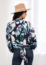 [Color: Navy/Teal] A model wearing a navy blue and teal watercolor print kimono wrap top. With long voluminous sleeves, an elastic wrist cuff, and a built in tie front that can be tied in multiple ways. 