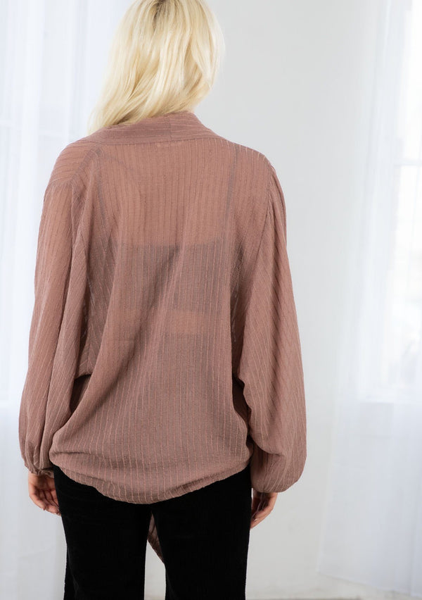 [Color: Dusty Rose] A model wearing a soft sheer dusty rose kimono top in a tonal shadow stripe. With long voluminous sleeves, elastic wrist cuffs, and a wrap tie front that can be tied in multiple ways. 