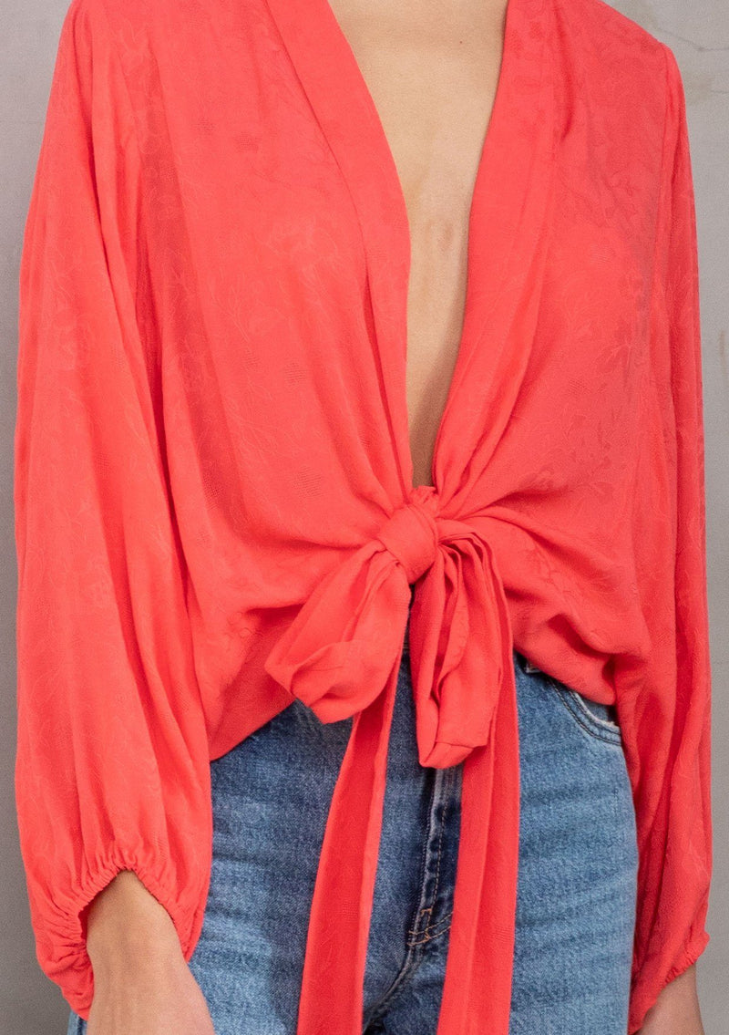 [Color: Hot Coral] A model wearing an elegant bright coral bohemian kimono top in textured floral jacquard. Features dolman sleeves, a deep v neckline and tie front. Can be tied in multiple ways.