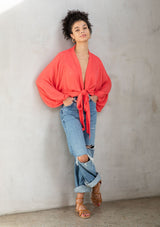 [Color: Hot Coral] A model wearing an elegant bright coral bohemian kimono top in textured floral jacquard. Features dolman sleeves, a deep v neckline and tie front. Can be tied in multiple ways.