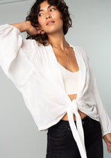 [Color: Ivory] A front facing image of a brunette model wearing an ivory white bohemian embroidered chiffon kimono top. With long sleeves and a tie front that can be styled in multiple ways. 