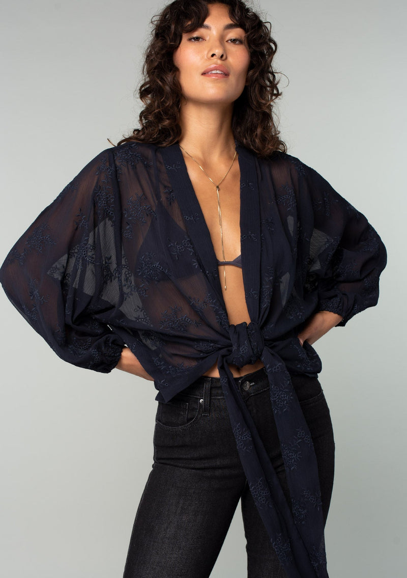[Color: Navy] A half body front facing image of a brunette model wearing a navy blue bohemian embroidered chiffon kimono top. With long sleeves and a tie front that can be styled in multiple ways. 