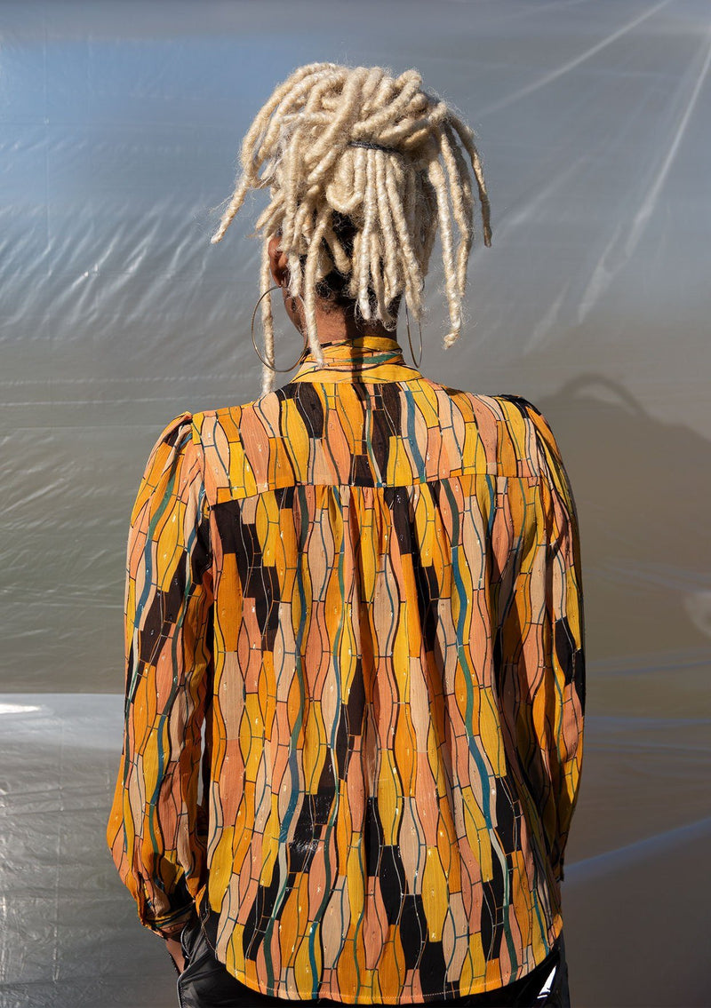 [Color: Honey Gold] A button up blouse in a vintage inspired tile print. Featuring a flirty ruffle yoke detail and a split neckline with ties. A subtle metallic detail throughout adds a little sparkle to this bohemian top. 
