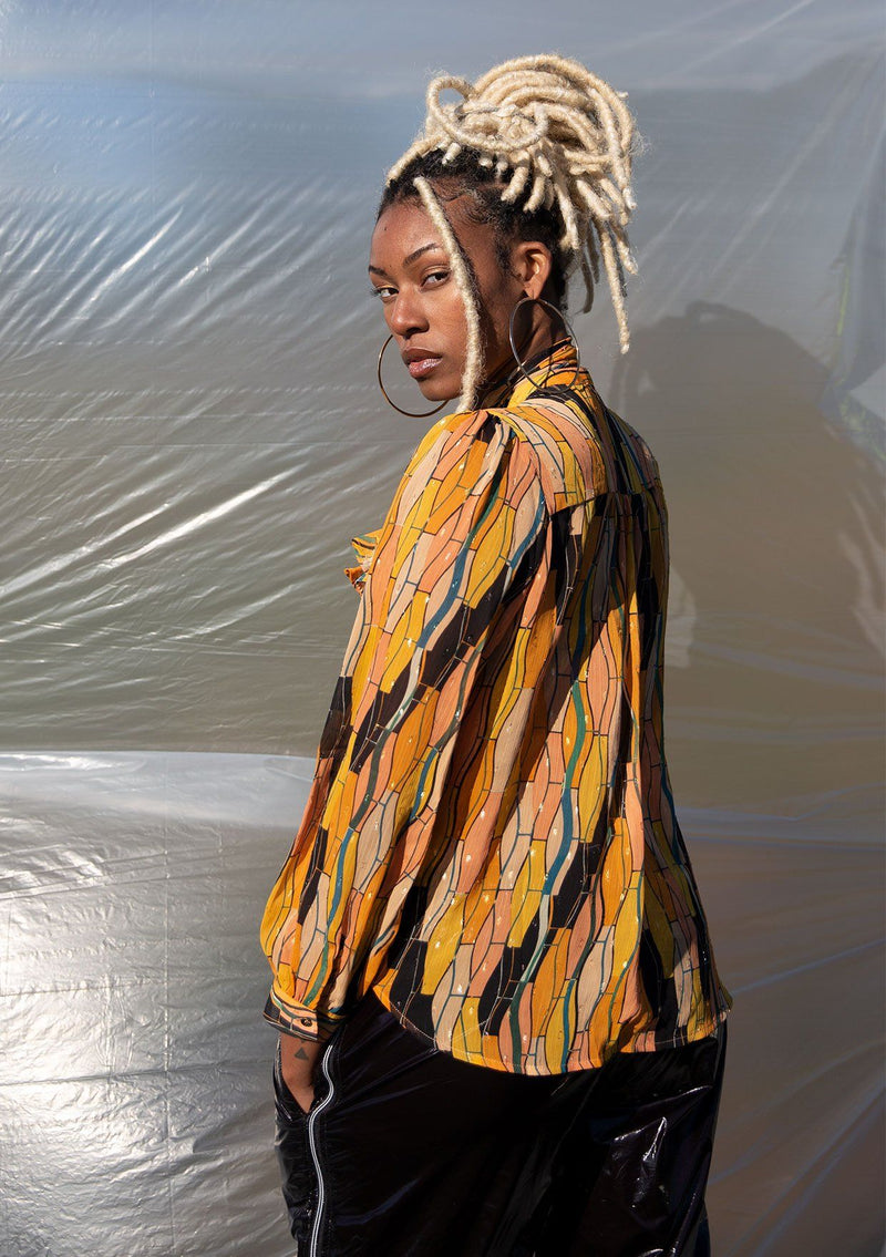 [Color: Honey Gold] A button up blouse in a vintage inspired tile print. Featuring a flirty ruffle yoke detail and a split neckline with ties. A subtle metallic detail throughout adds a little sparkle to this bohemian top. 