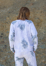[Color: Grey Combo] A woman standing outside wearing a classic cotton sweatshirt in a splatter tie dye wash. Featuring a crew neckline, long raglan sleeves, and a relaxed fit. 