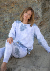 [Color: Grey Combo] A woman standing outside wearing a classic cotton sweatshirt in a splatter tie dye wash. Featuring a crew neckline, long raglan sleeves, and a relaxed fit. 