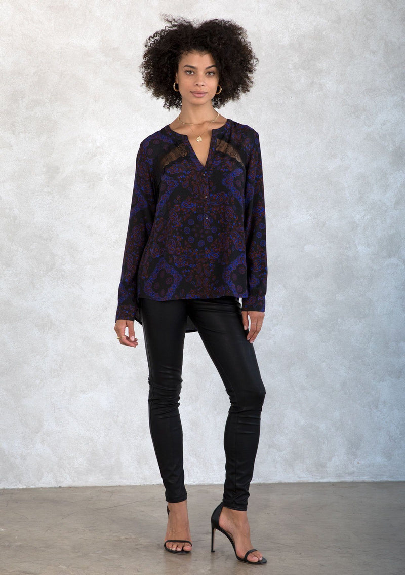 [Color: Black/Cobalt] A model wearing a classic lace trimmed button front top in a black and blue paisley bandana print. With a sheer lace insert across the yoke. 