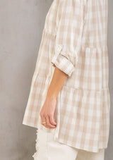 [Color: Taupe/White] A model wearing a relaxed cotton blend beige large gingham button up tunic, with a rolled sleeve, a tiered body, and a long tunic length.