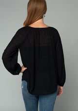 [Color: Black] A back facing image of a red headed model wearing a black bohemian peasant top in embroidered chiffon. With long sleeves, lattice trim, a v neckline, a button front, and a flowy relaxed fit. 