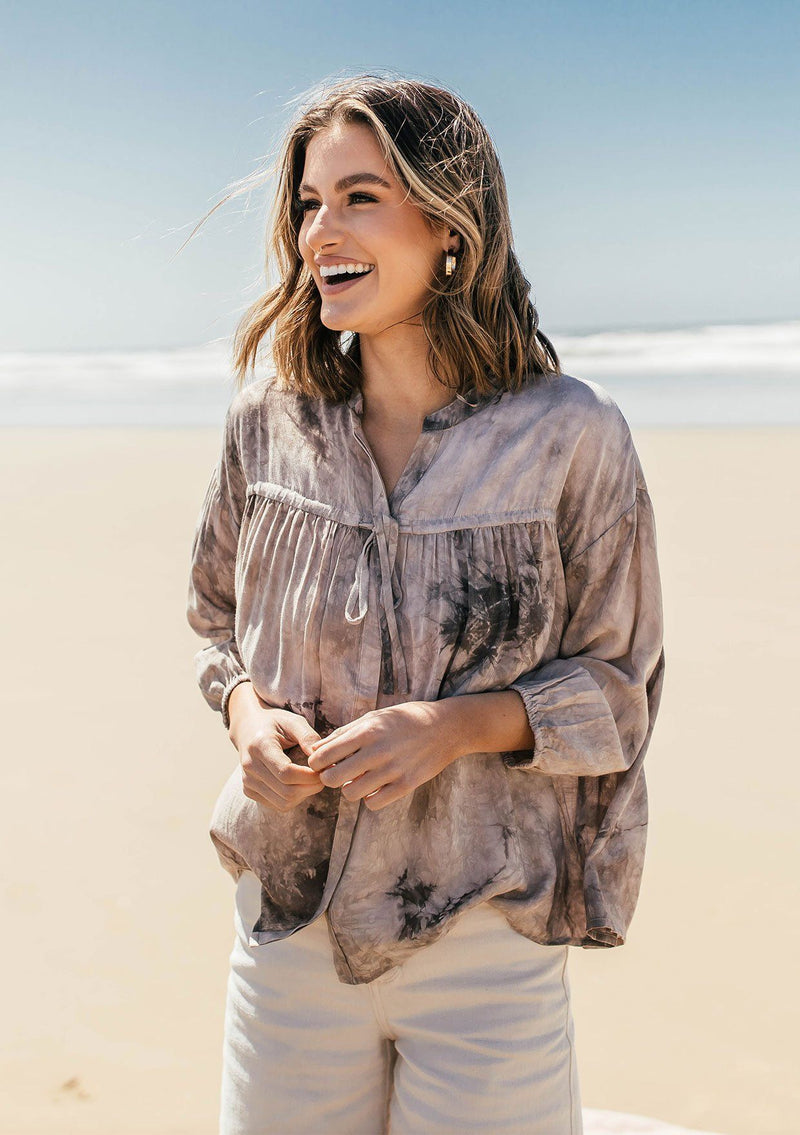 [Color: Cement] A classic peasant blouse in dreamy tie dye. Featuring voluminous three quarter length sleeves, a flattering v neckline, and a hidden button up front.