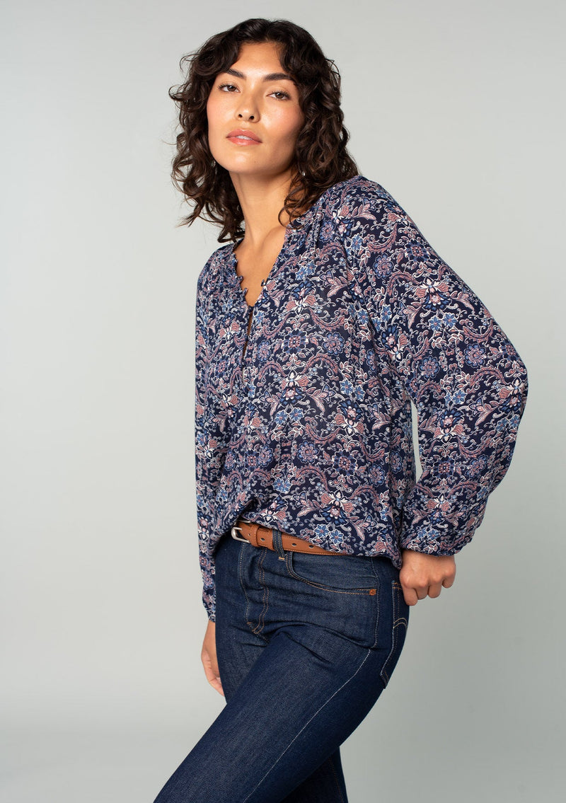 [Color: Navy/Tan] A front facing image of a brunette model wearing a navy and tan paisley print peasant top. A classic flowy bohemian blouse with long sleeves, a loop button front, and elastic wrist cuffs. 