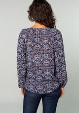[Color: Navy/Tan] A back facing image of a brunette model wearing a navy and tan paisley print peasant top. A classic flowy bohemian blouse with long sleeves, a loop button front, and elastic wrist cuffs. 