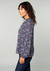 [Color: Navy/Tan] A side facing image of a brunette model wearing a navy and tan paisley print peasant top. A classic flowy bohemian blouse with long sleeves, a loop button front, and elastic wrist cuffs. 