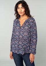 [Color: Navy/Tan] A half body front facing image of a brunette model wearing a navy and tan paisley print peasant top. A classic flowy bohemian blouse with long sleeves, a loop button front, and elastic wrist cuffs. 