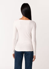 [Color: Nude] A back facing image of a brunette model wearing an off white bamboo micro ribbed long sleeve tee. Featuring a mock neckline and a stretchy slim fit.
