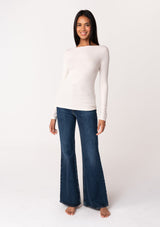 [Color: Nude] A full body front facing image of a brunette model wearing an off white bamboo micro ribbed long sleeve tee. Featuring a mock neckline and a stretchy slim fit.