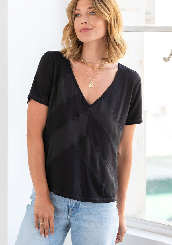 [Color: Black] A model wearing a classic short sleeve v neck tee shirt. With sheer diagonal panels along the front.
