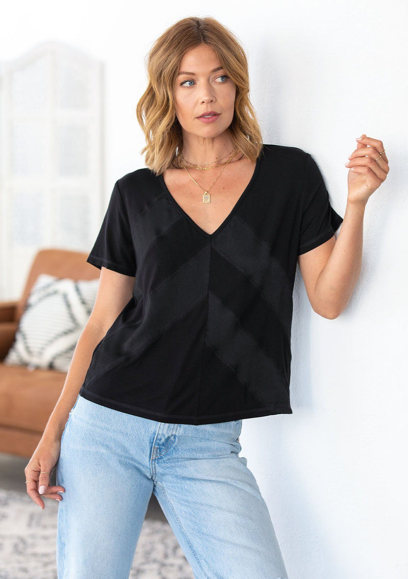 [Color: Black] A model wearing a classic short sleeve v neck tee shirt. With sheer diagonal panels along the front.
