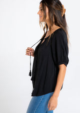 [Color: Black] A model wearing a black puff sleeve button front blouse.