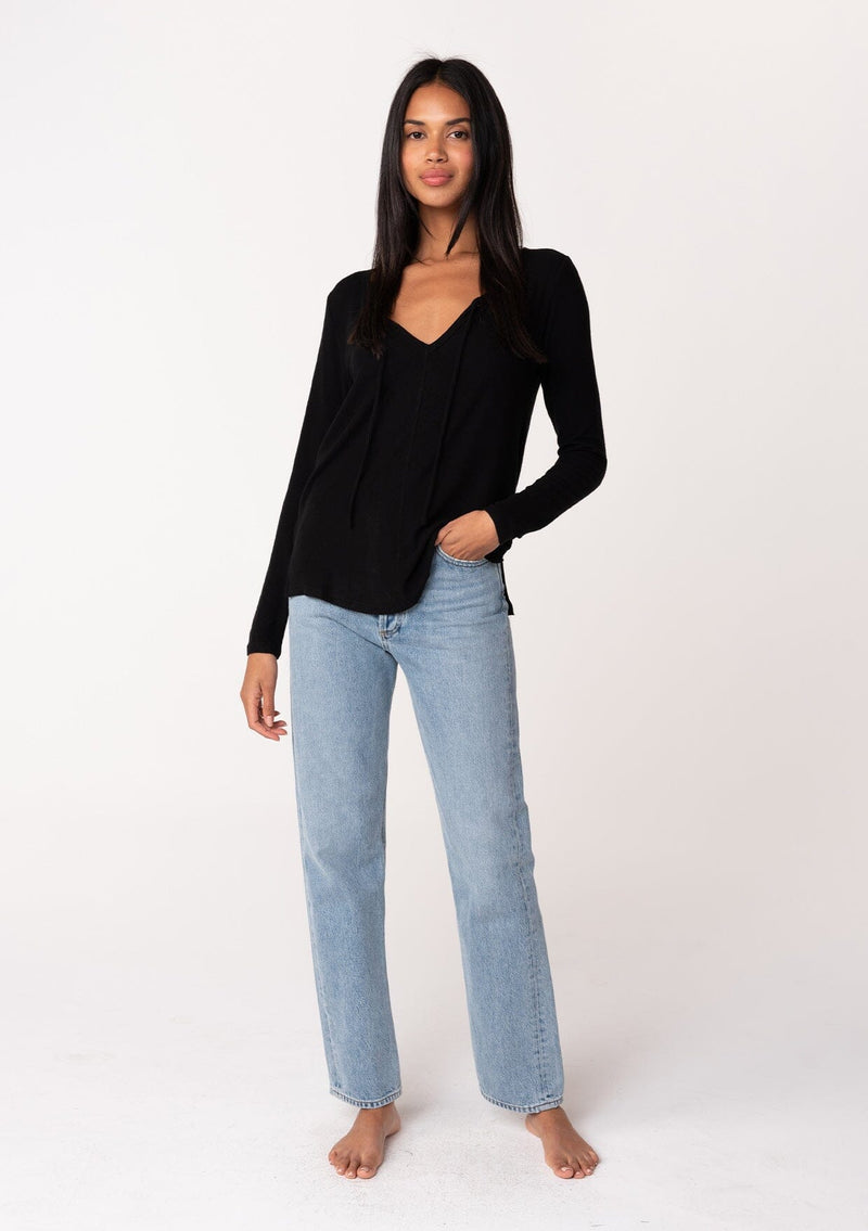 [Color: Black] A full body front facing image of a model wearing a black micro rib long sleeve tee with a v neckline and neck ties. 