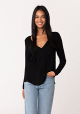 [Color: Black] A front facing image of a model wearing a black micro rib long sleeve tee with a v neckline and neck ties. 