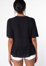 [Color: Black] A model wearing a flowy black short sleeve top.