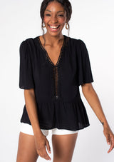 [Color: Black] A model wearing a flowy black short sleeve top.