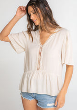 [Color: Vanilla Bean] A model wearing a flowy cream colored short sleeve top. 