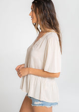 [Color: Vanilla Bean] A model wearing a flowy cream colored short sleeve top. 