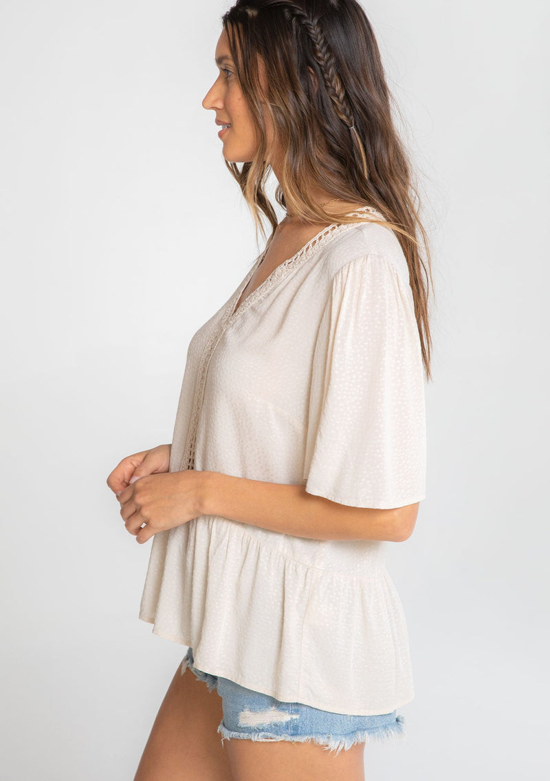 [Color: Vanilla Bean] A model wearing a flowy cream colored short sleeve top. 