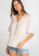 [Color: Vanilla Bean] A model wearing a flowy cream colored short sleeve top. 