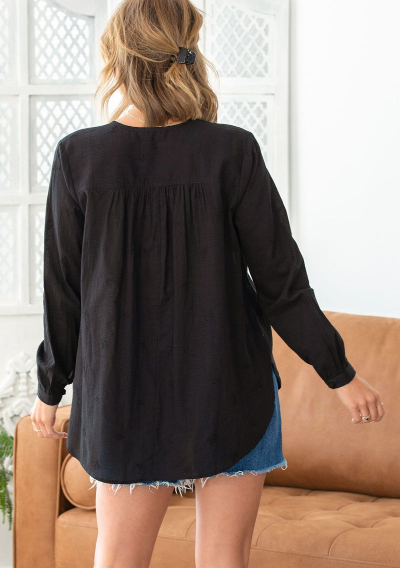 [Color: Black] A woman wearing a sheer cotton voile button front top. Featuring pretty floral embroidered details throughout, voluminous long sleeves with a button cuff closure, and a large button up front.