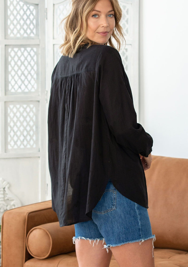 [Color: Black] A woman wearing a sheer cotton voile button front top. Featuring pretty floral embroidered details throughout, voluminous long sleeves with a button cuff closure, and a large button up front.