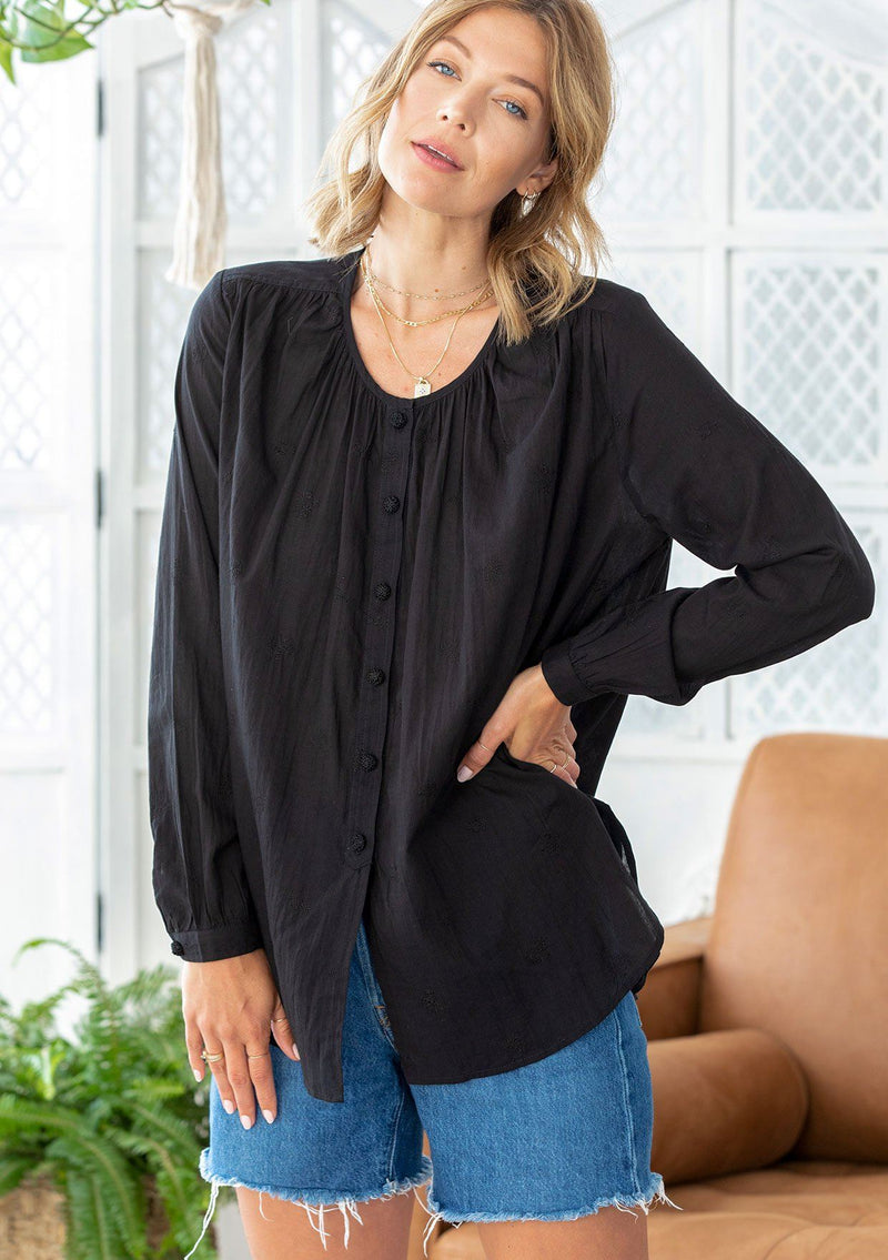 [Color: Black] A woman wearing a sheer cotton voile button front top. Featuring pretty floral embroidered details throughout, voluminous long sleeves with a button cuff closure, and a large button up front.
