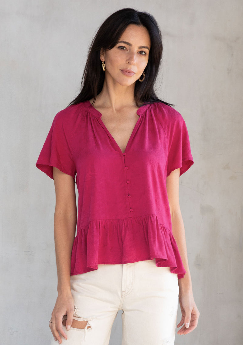 [Color: Mulberry] A model wearing a pink bohemian rose jacquard button front top with a v neckline, short flutter sleeves, and a peplum waist.