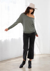 [Color: Army Green] A model wearing an army green French terry top. With long dolman sleeves and a boat neckline that can be worn on or off the shoulder. 