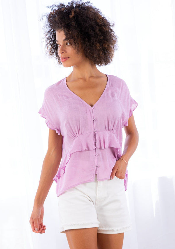 [Color: Lilac] A model wearing a lightweight, lilac looped button front bohemian top in textured paisley jacquard. With short ruffled cap sleeves and a ruffle waist detail. 