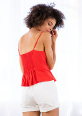 [Color: Scarlet] A model wearing a bright red camisole tank top made from a linen blend. With a sweetheart neckline, a button front, a peplum waist, and a slimming half smocked elastic waist. 