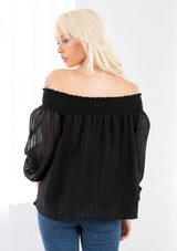 [Color: Black] A model wearing a bohemian black off shoulder top in a sheer shadow stripe. With long voluminous sleeves, a smocked elastic wrist cuff, and a smocked elastic off shoulder neckline. 