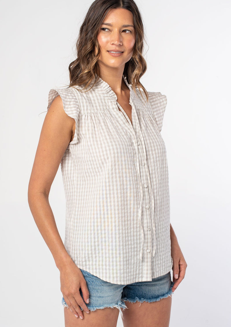 [Color: Pebble/Ivory] A woman wearing a cotton taupe and white gingham check print top with a button front and short flutter sleeves. 