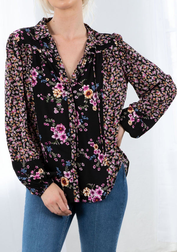 [Color: Black/Wine] A model wearing a classic bohemian button front blouse. With long voluminous sleeves, elastic wrist cuffs, a collared neckline with ties, and contrast ditsy floral print details. 
