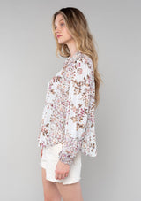 [Color: Mint/Rose] A side facing image of a blonde model wearing a vintage inspired bohemian blouse in a pink mixed floral print. With long sleeves, a collared neckline with ties, a self covered button front, and a flowy relaxed fit. 