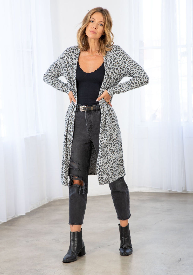 [Color: Heather Grey/Charcoal] A model wearing an ultra soft Hacci knit mid length cardigan in a leopard print. With long sleeves, an open front, and side pockets. 
