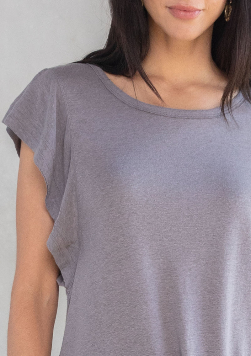 [Color: Smoke] A model wearing a grey linen blend tee shirt with a short ruffled sleeve. 