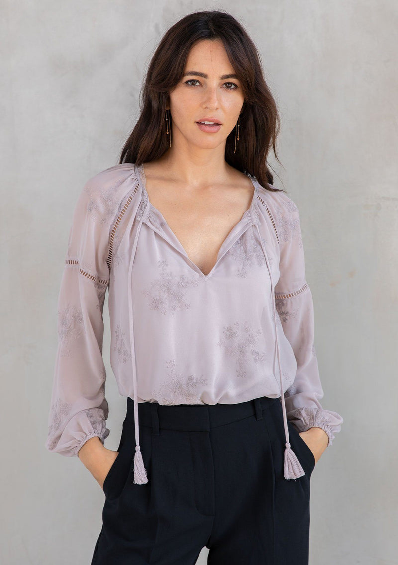 [Color: Dusty Mauve] A model wearing a dreamy sheer chiffon blouse with floral embroidered details throughout. With long voluminous sleeves and lace trim.