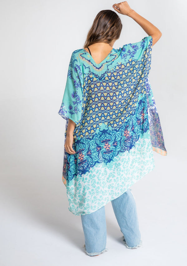 [Color: Aqua/Navy] A model wearing an abstract aqua and navy blue floral print mid length kimono. With half length kimono sleeves, an open front, and side slits.