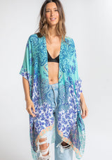 [Color: Aqua/Navy] A model wearing an abstract aqua and navy blue floral print mid length kimono. With half length kimono sleeves, an open front, and side slits.