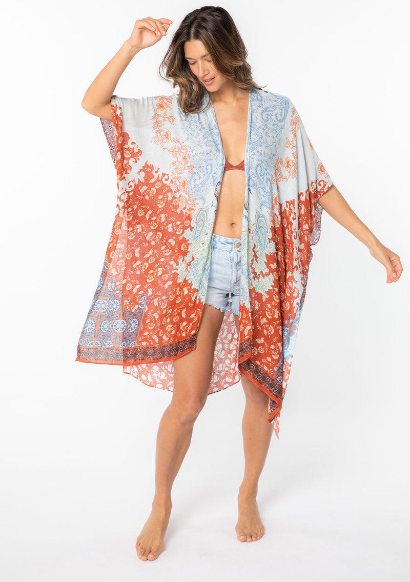 [Color: Light Blue/Red] A model wearing an abstract blue and red floral print mid length kimono. With half length kimono sleeves, an open front, and side slits.